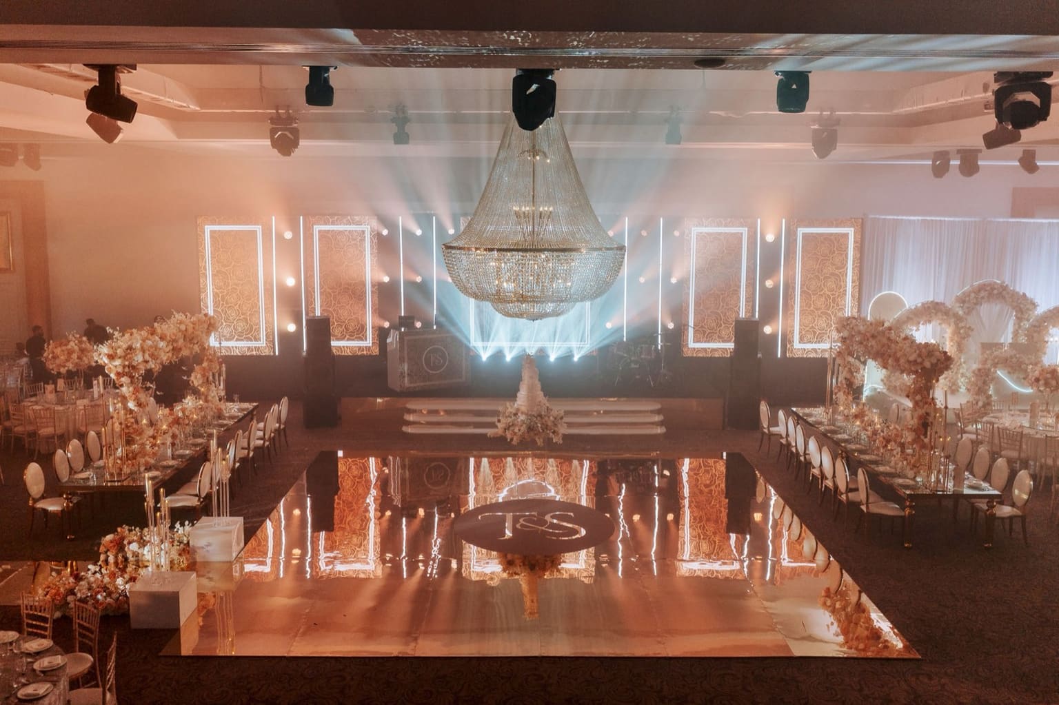 The Meridian Grand ballroom dressed for a wedding reception — a crystal chandelier above a mirrored dance floor, with floral displays and banquet tables.